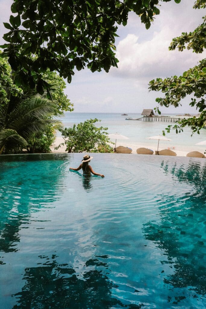 Frau im Infinity-Pool mit dem Meeresblick